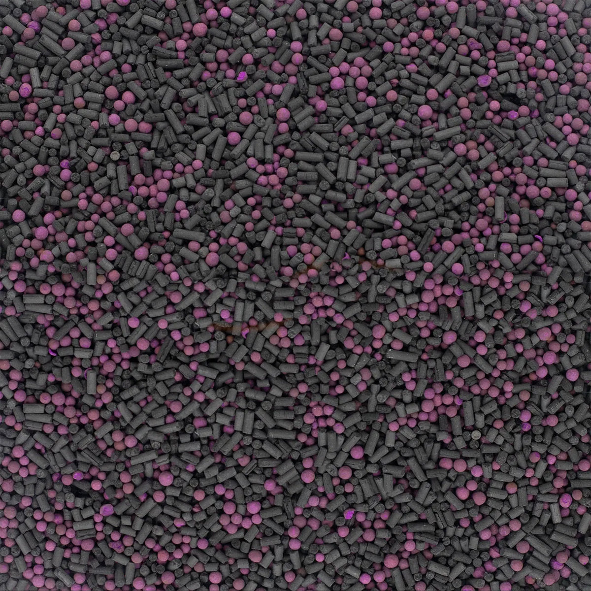 Nahaufnahme des Filtergranulats aus schwarzen Aktivkohle-Pellets und pinken Kügelchen des IQAir HealthPro 250 XE