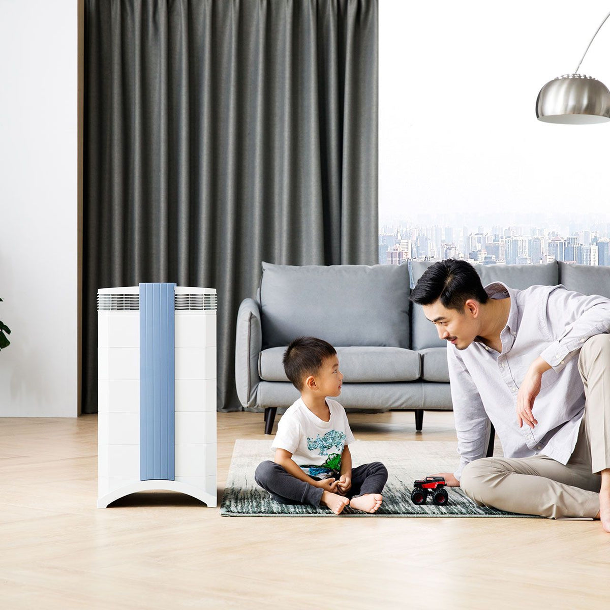 IQAir GC MultiGas XE Luftreiniger in Weiß im Wohnzimmer, Vater und Sohn spielen daneben auf dem Teppich