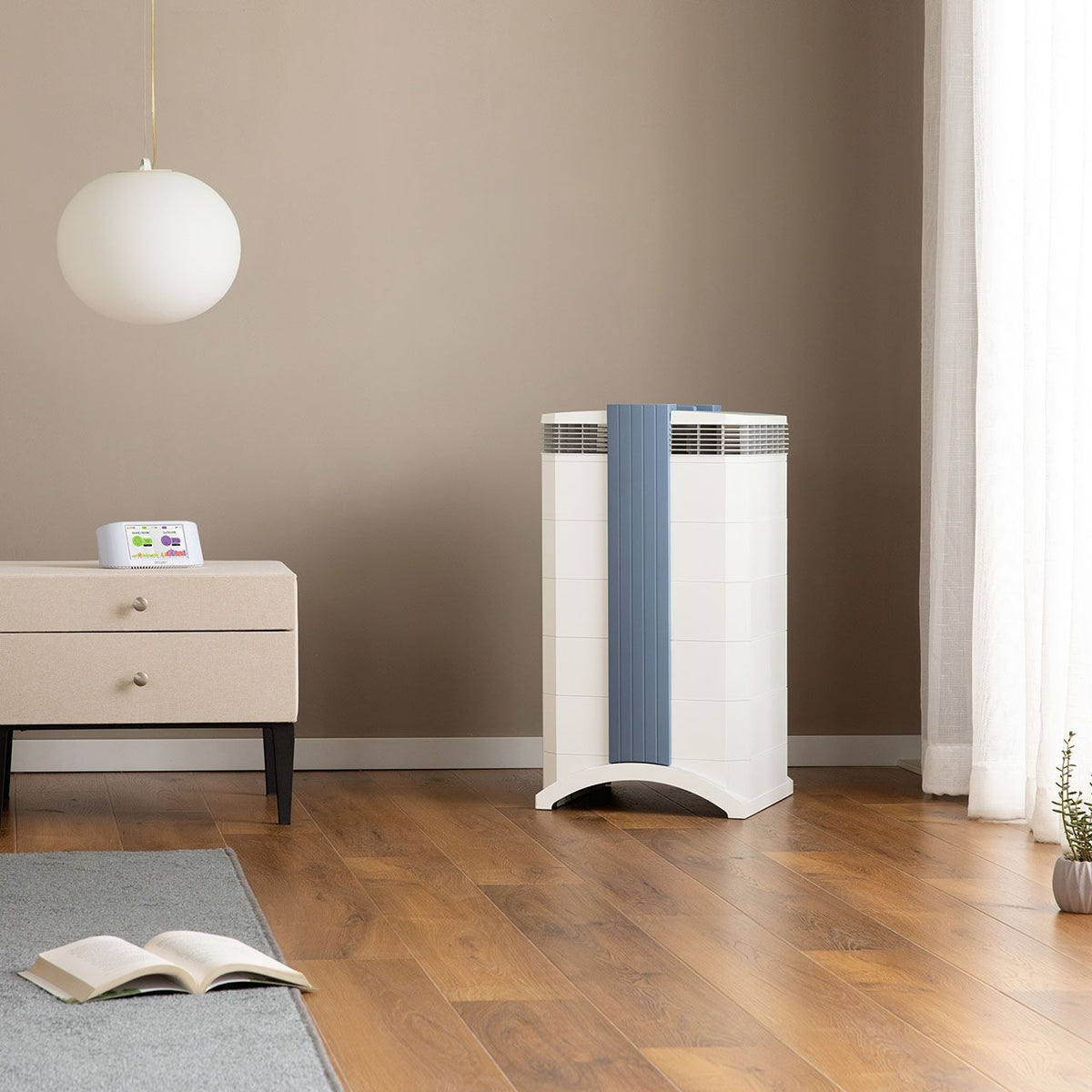 IQAir GC MultiGas XE Luftreiniger, weiß mit blauem Griffelement, im Schlafzimmer neben Kommode