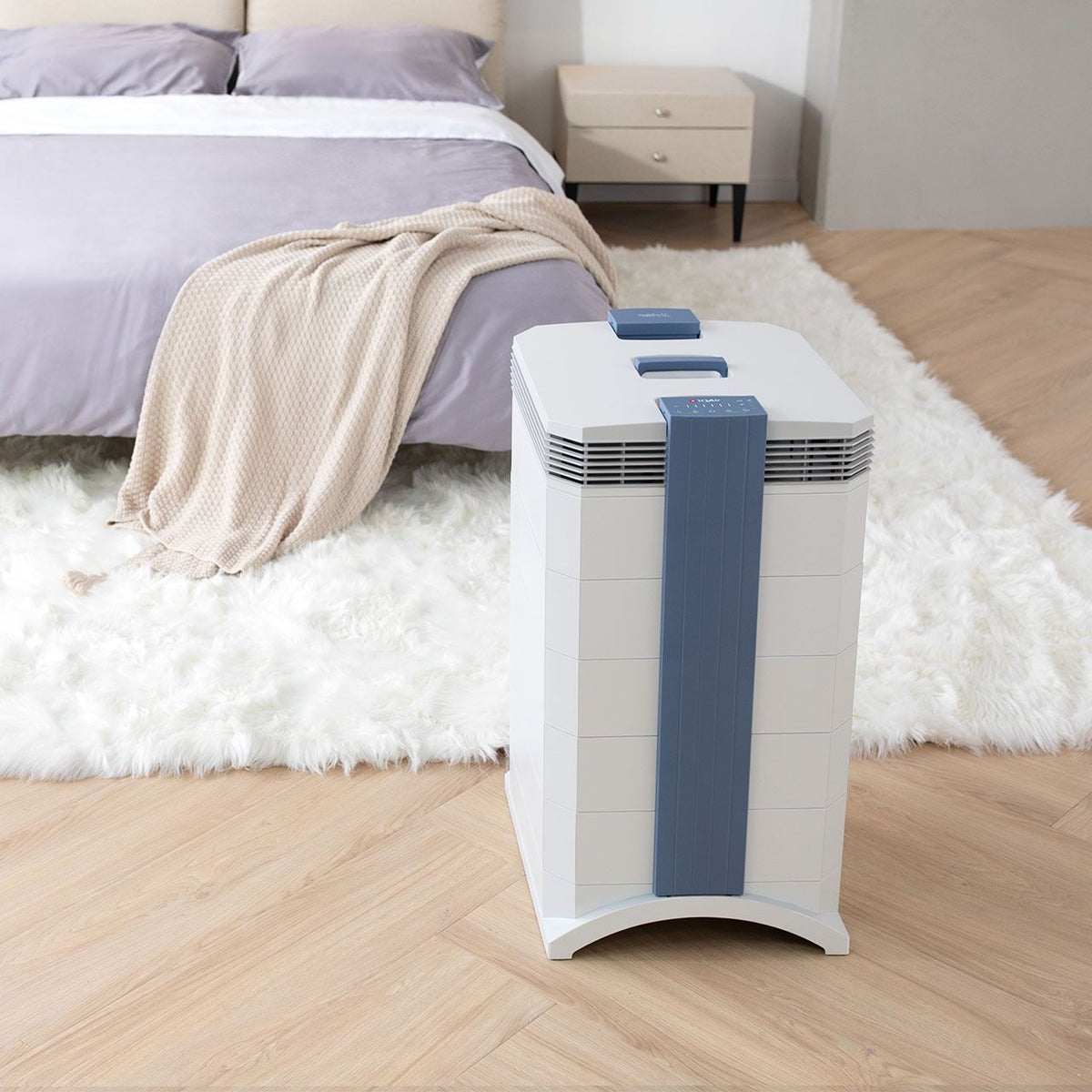 IQAir GC XE MultiGas Luftreiniger in Weiß auf Fellteppich neben Bett im Schlafzimmer