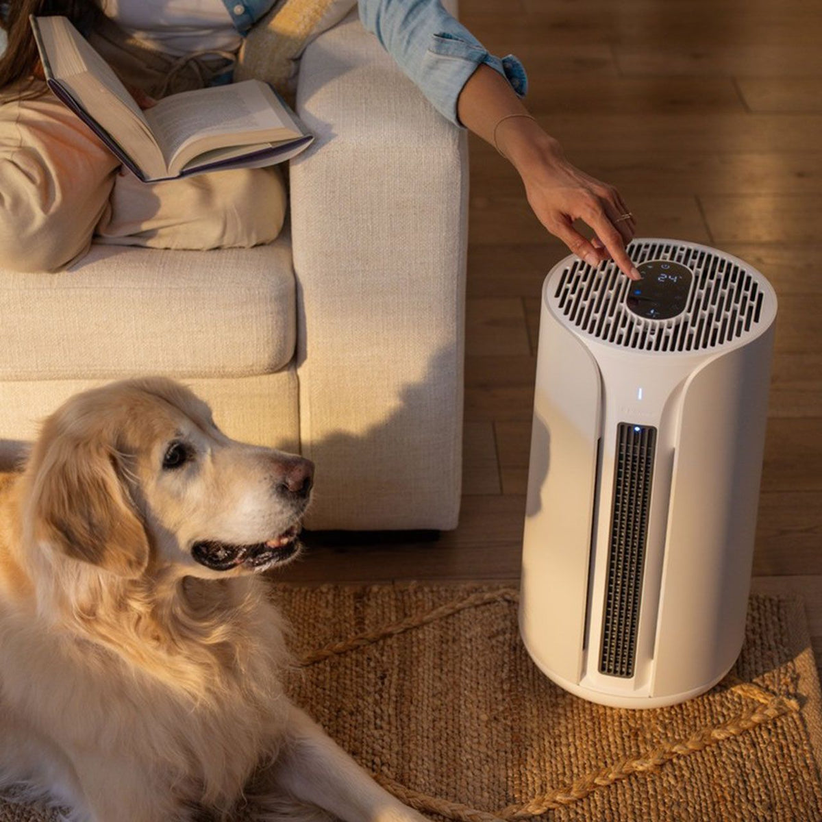 Blueair ComfortPure T10i Luftreiniger im Wohnzimmer, Frau bedient Display, Hund liegt daneben