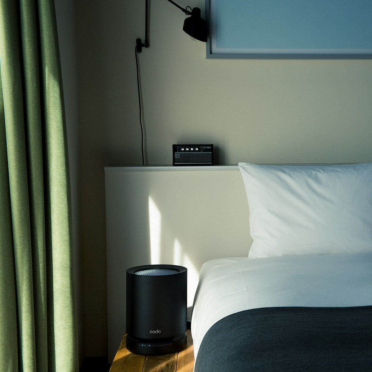 Cado LEAF 120 Luftreiniger in Schwarz auf Holztisch neben Bett im Schlafzimmer