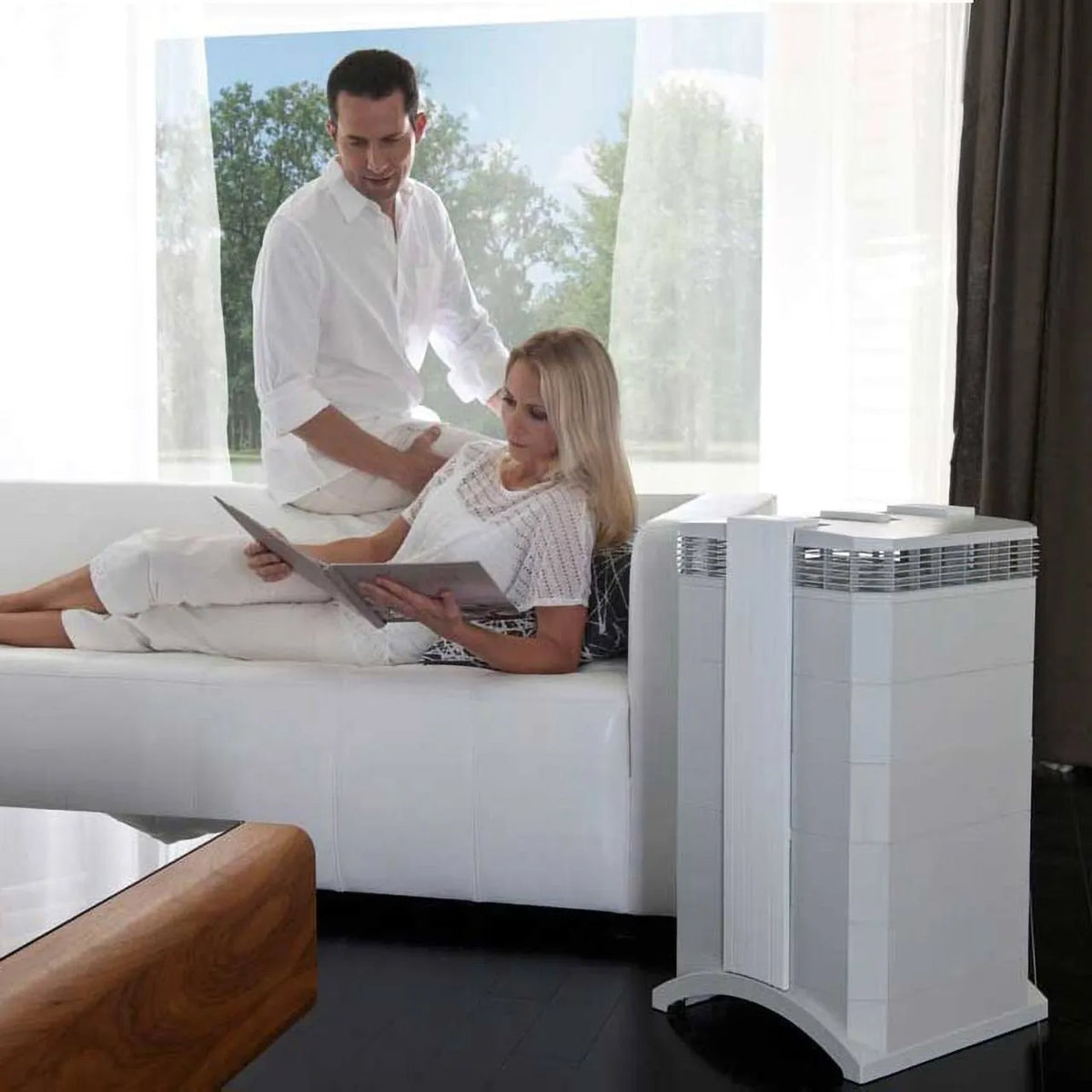 IQAir HealthPro 250 NE Luftreiniger im Wohnzimmer neben Sofa mit lesendem Paar