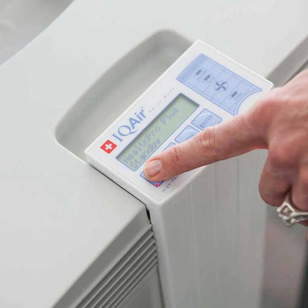 Nahaufnahme des Bedienfelds des IQAir HealthPro 250 NE Luftreinigers, Finger bedient Display