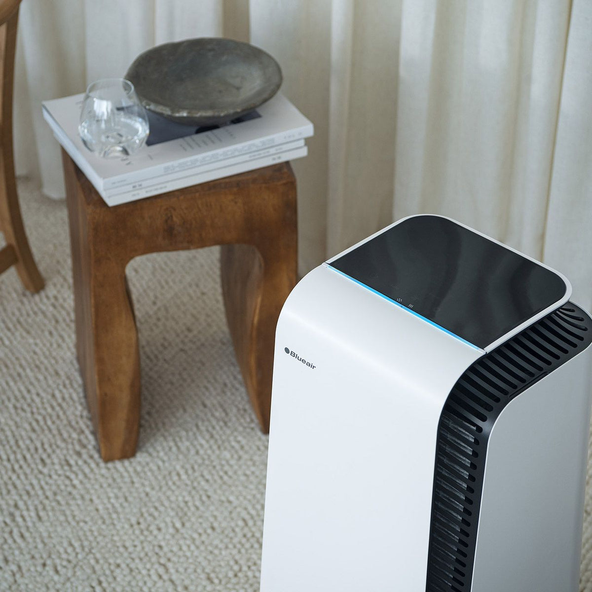 Blueair HealthProtect 7740i Luftreiniger in Weiß neben Holzhocker im Wohnraum